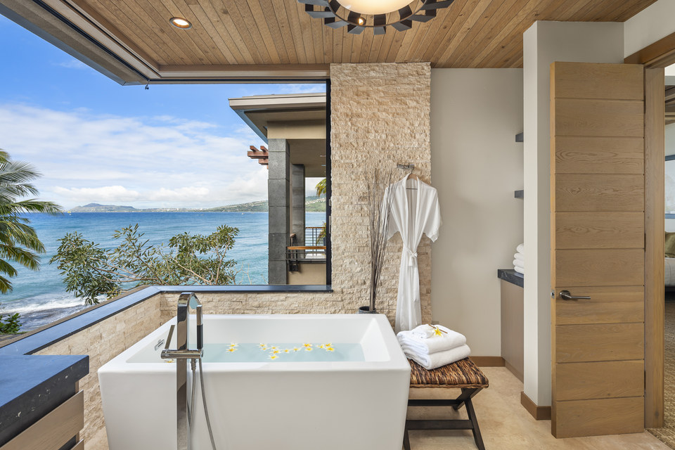 Oceanfront bath terrace framed by stone, wood and tropical planting at a Hawaiʻi residence.