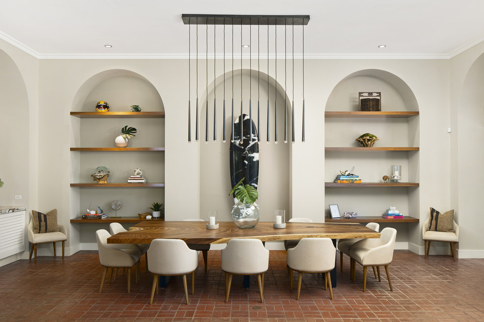 Symmetrical dining room with arched niches, a live-edge table and linear pendant lighting.