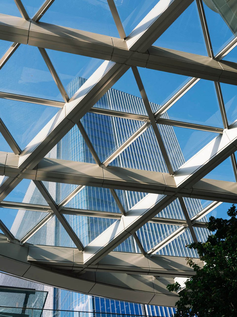 Geometric glass-and-steel canopy framing modern towers in Tokyo.