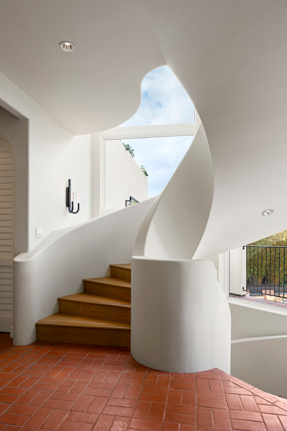 Sculptural white staircase with terracotta flooring in a Hawaiʻi residence.