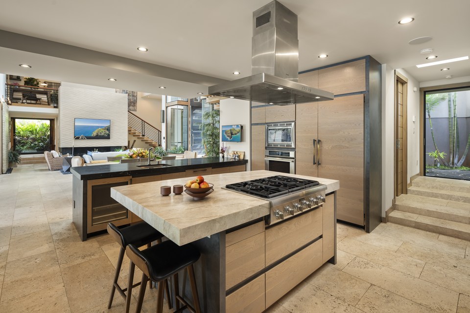 Open kitchen with wood cabinetry, dark stone and a central island.