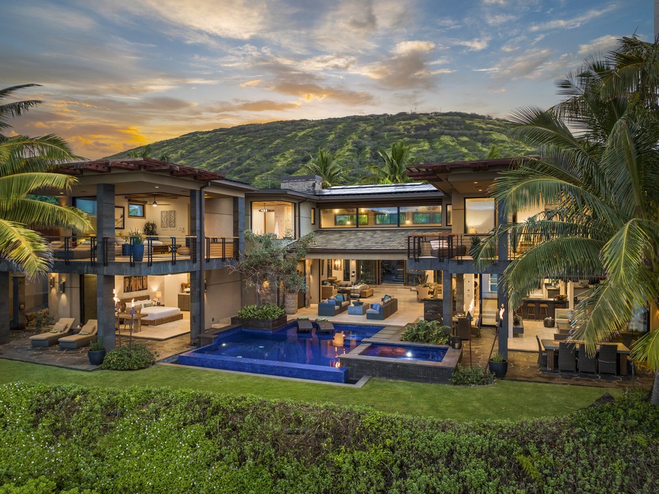 Oceanfront residence and illuminated pool at twilight.