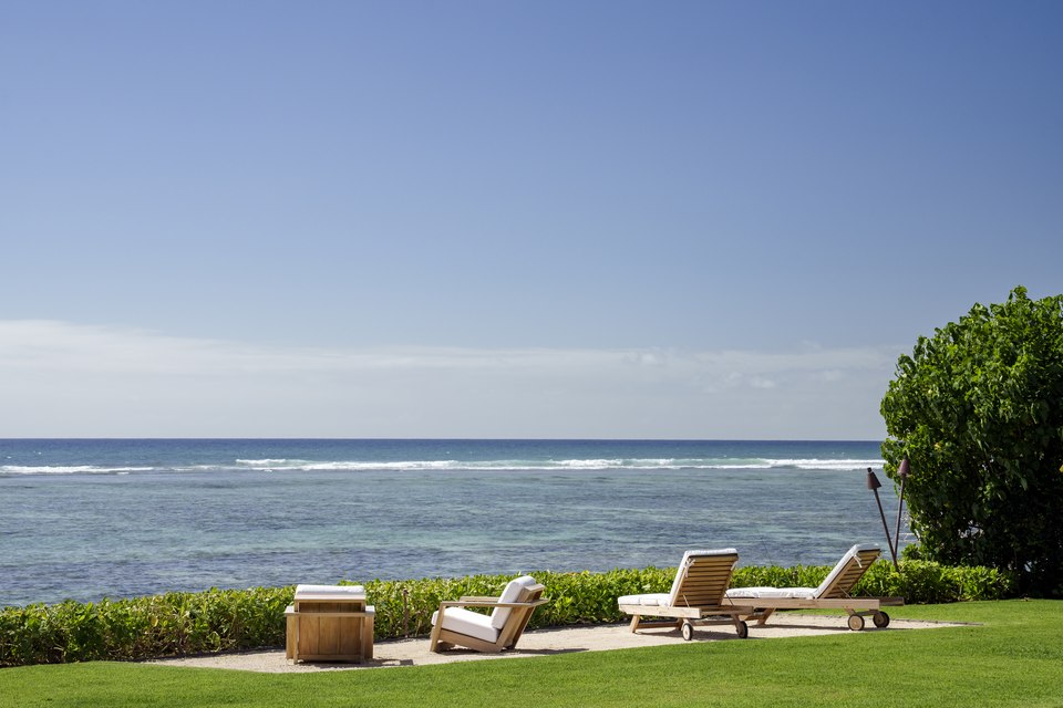 Oceanfront lounge chairs arranged at the edge of the lawn.