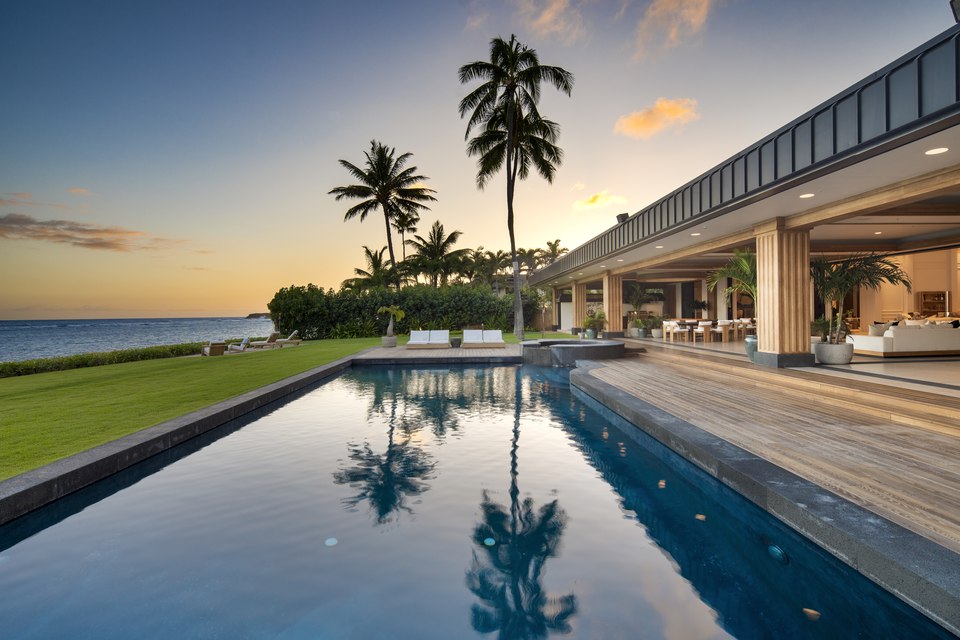 Oceanfront pool, lawn and open-air living spaces at dusk at 4505 Kahala Avenue.