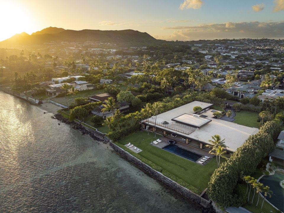Sunset aerial view of the oceanfront residence and neighborhood.