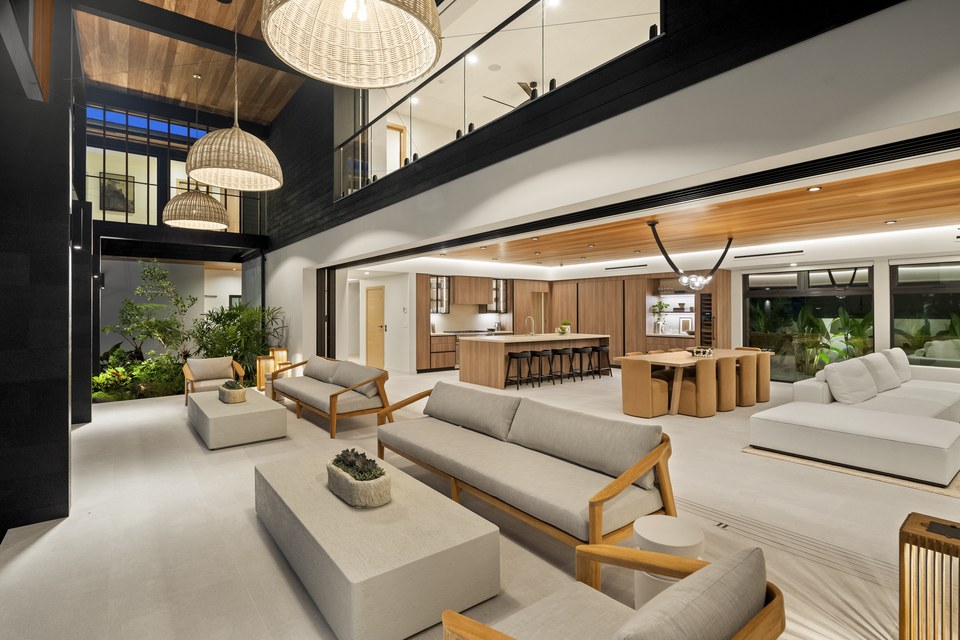 Double-height indoor-outdoor living room with woven pendant lights and garden views.