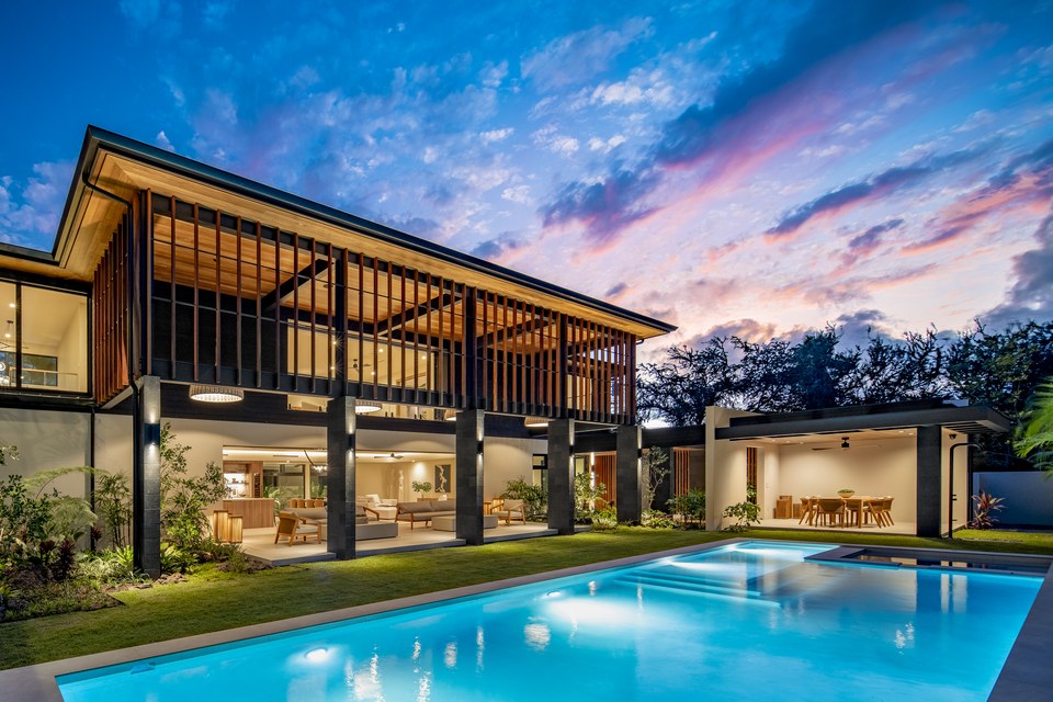 Contemporary Kāhala residence opening to its illuminated pool courtyard at twilight.