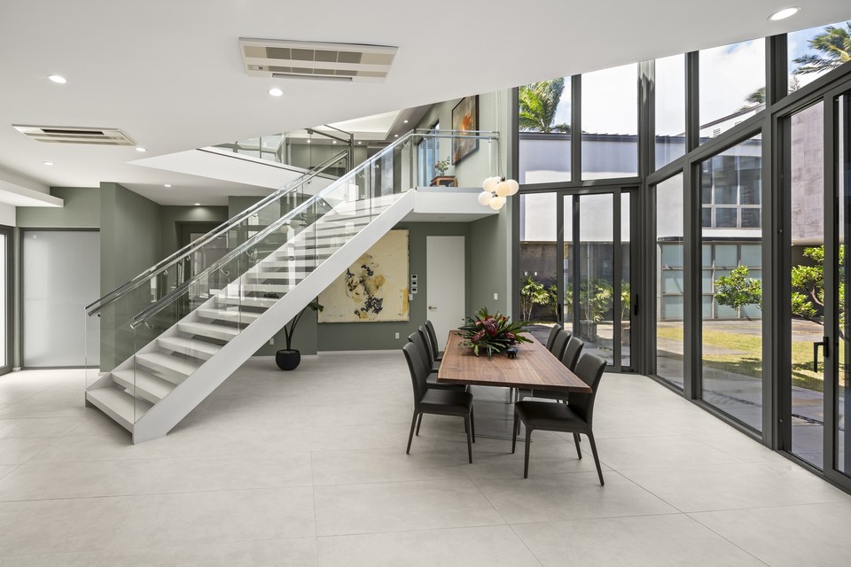 Open dining area and glass staircase beneath a double-height window wall.