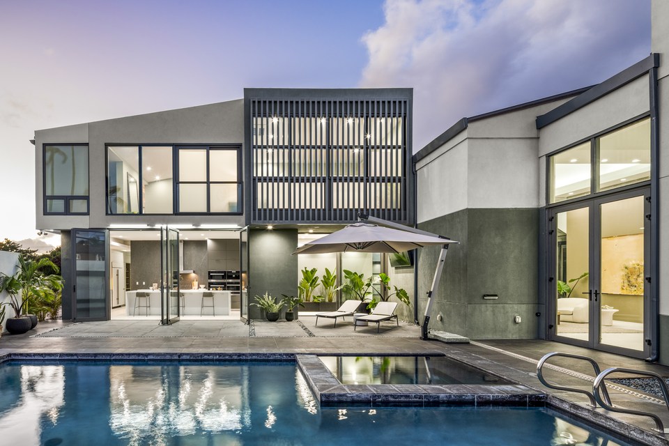 Contemporary Kāhala residence and pool at twilight.