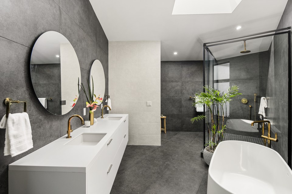 Primary bathroom with dark stone walls and freestanding tub.