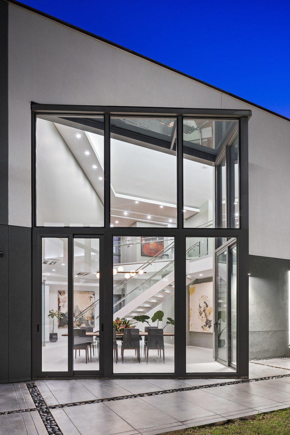 Two-story glass facade revealing the stair and interior spaces of a Kahala residence.