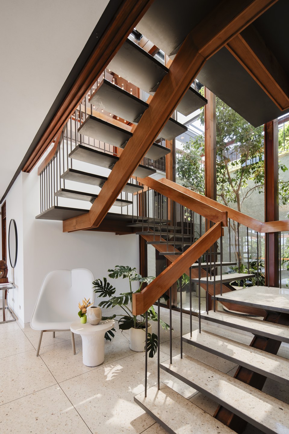 Sculptural staircase with dark timber, glass and stone detailing.