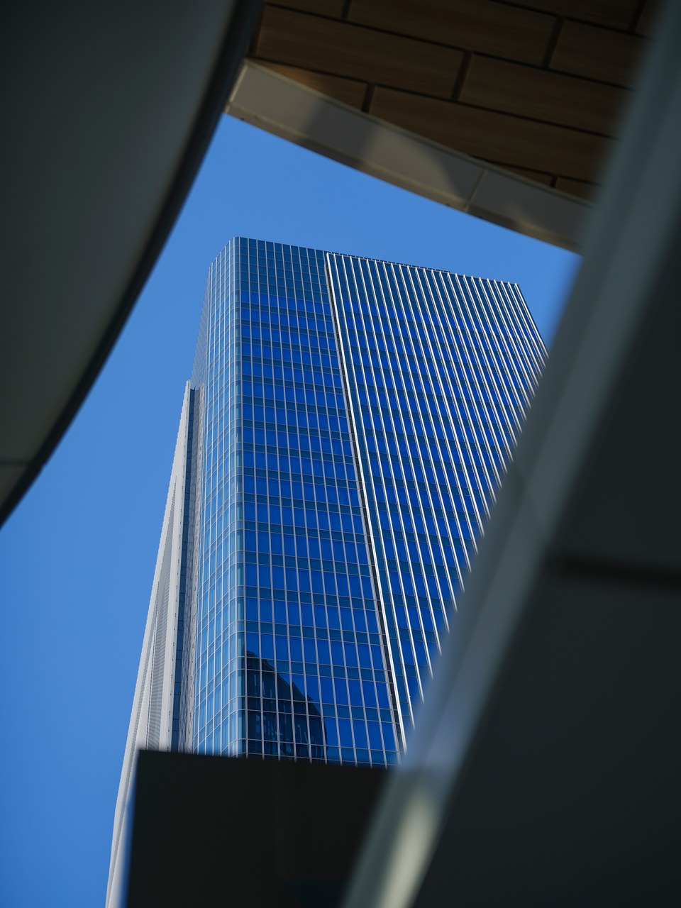 Blue-glass Tokyo tower framed by a sweeping architectural opening.