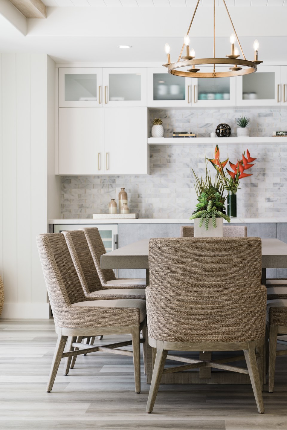 Bright dining room with woven chairs, tailored millwork and tropical flowers.